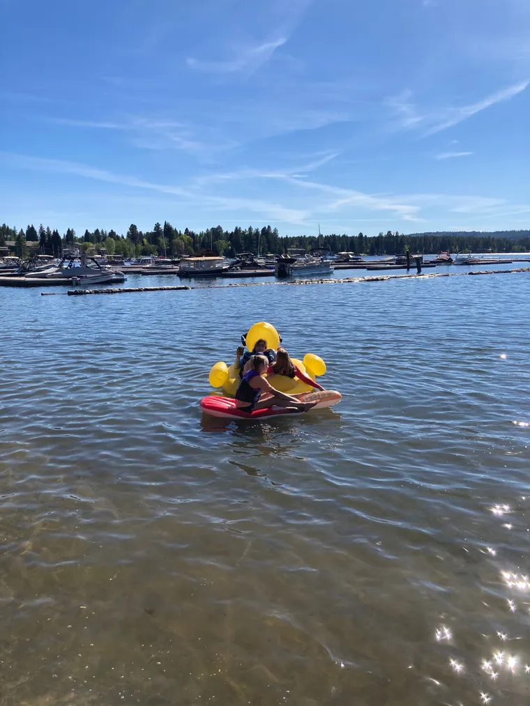 Photo of three girls floating on inflatables in a lake.